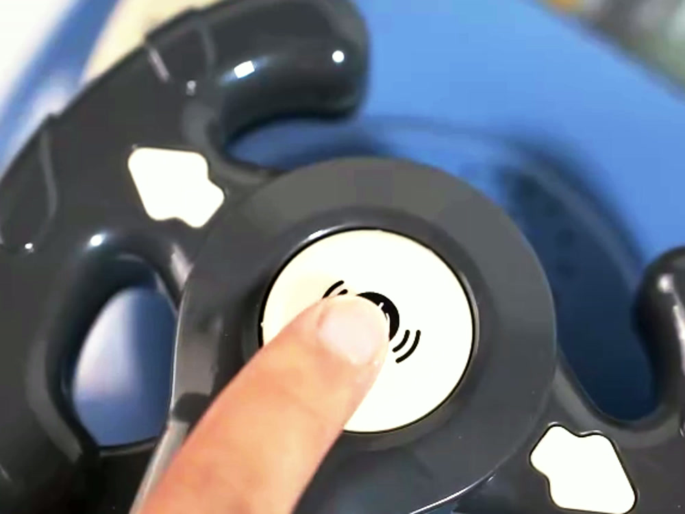 A finger pressing the horn button on the steering wheel